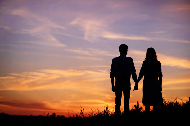 istock young couple is holding hands on a background sunset silhouette 850429386