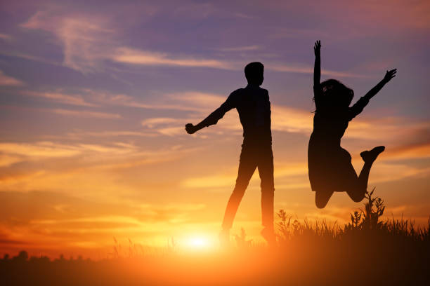 istock A young man with his girlfriend jump on background sunset silhouette 850429394