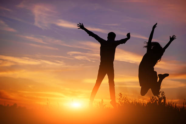 istock A young man with his girlfriend jump on background sunset silhouette 850429404
