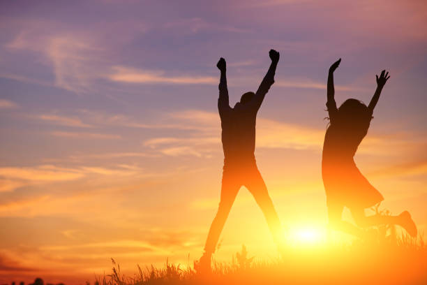 istock A young man with his girlfriend jump on background sunset silhouette 850429420