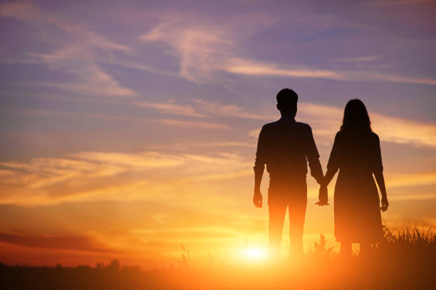 istock young couple is holding hands on a background sunset silhouette 850429428