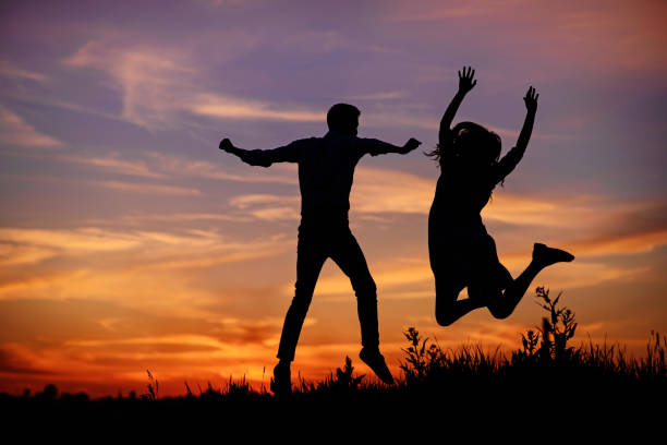 istock A young man with his girlfriend jump on background sunset silhouette 850429438