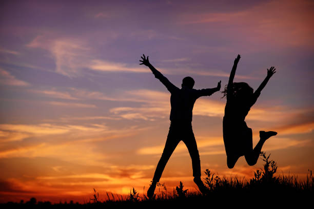 istock A young man with his girlfriend jump on background sunset silhouette 850429464