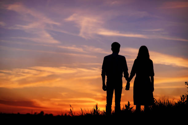 istock young couple is holding hands on a background sunset silhouette 850429494