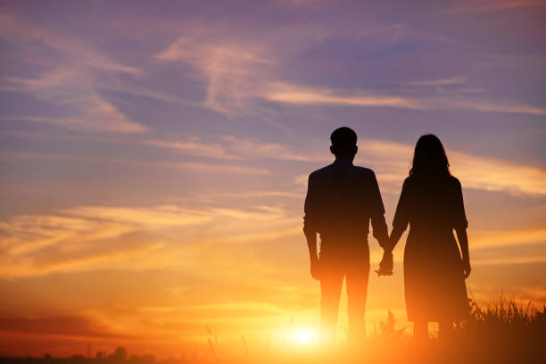 istock young couple is holding hands on a background sunset silhouette 850429496