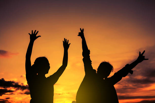 Silhouette of a mother and son dancing in a field at sunset