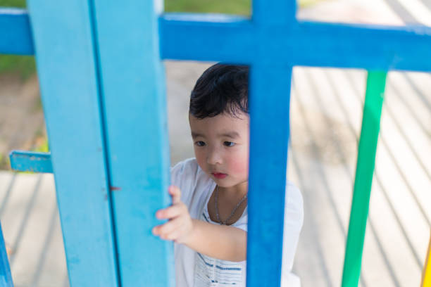 istock Sad Asian kid behind the grid trying to escape. shallow DOF 850642818