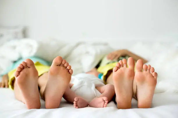 Photo of Little baby boy feet, baby lie down in bed in the afternoon