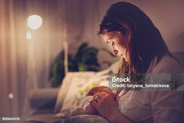 Young Beautiful Mother Breastfeeding Her Newborn Baby Boy At Night Stock Photo - Download Image Now