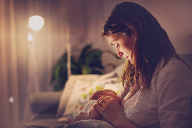 年輕美麗的母親、 母乳餵養她晚上的初生男嬰 - 餵人奶 個照片及圖片檔
