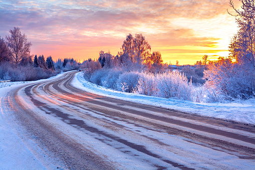 winter landscape with sunset,road and forest. path winter covered with snow in rays of sunset. wintry snowy road in ice