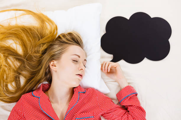 Young woman lying on bed wearing pajamas Teenage sleepwear fashion concept. Young woman lying on bed wearing cute pink pajamas, black thinking or speech bubble next to her. hhh stock pictures, royalty-free photos & images