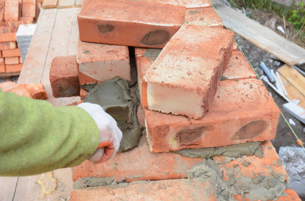 istock Bricklayer Worker Installing Red Blocks and Caulking Brick Masonry Joints Exterior Wall with Trowel putty Knife. Bricklaying Masonry. Brick masonry. 850696680