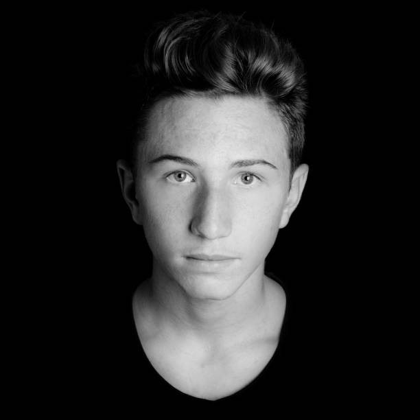 young serious guy portrait on black background - black and white photo stock photo