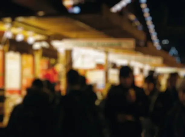 Illuminated Christmas fair kiosk market stall with loads of lovely handcrafted signs for home made crepes and sweet food people walking blur, bokeh, defocused