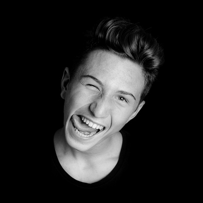 young guy tongue out portrait on black background - black and white photo