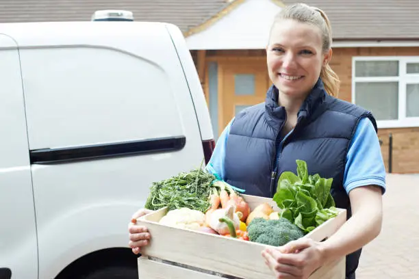 Woman Making Home Delivery Of Organic Vegetable Box