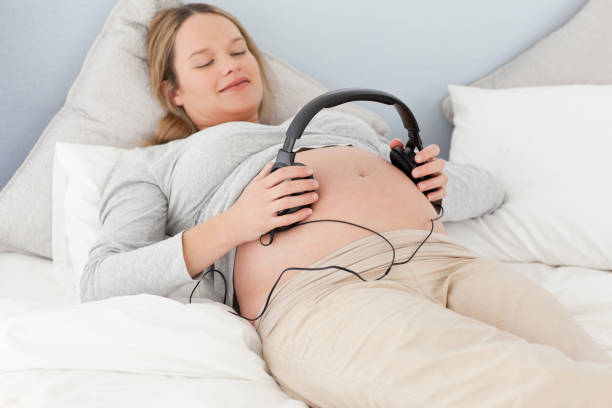 istock Happy future mom putting headphones on her belly 850760666
