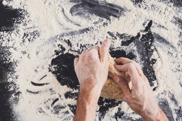 istock Hands top view knead dough on black background 850777420
