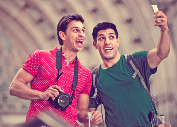 Two cheerful positive  friends are walking with baggage and making selfie in Barcelona.