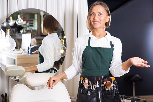 Portrait of adult woman makeup artist standing in the salon