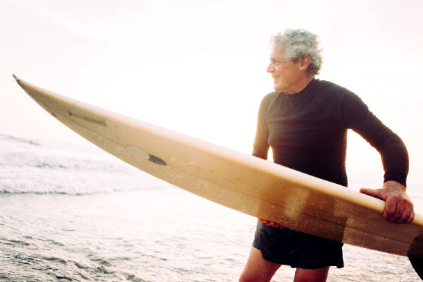 uomo anziano che naviga - senior adult surfing aging process sport foto e immagini stock
