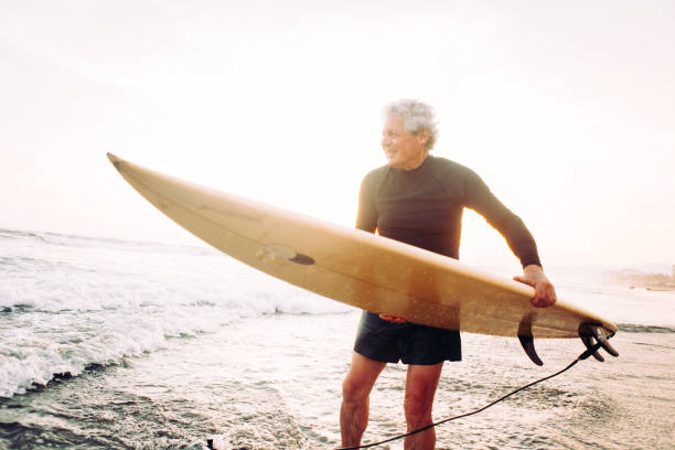 uomo anziano che naviga - senior adult surfing aging process sport foto e immagini stock