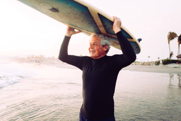 uomo anziano che naviga - senior adult surfing aging process sport foto e immagini stock