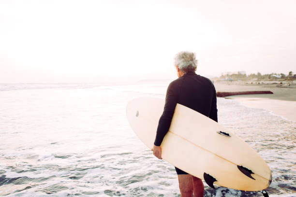 uomo anziano che naviga - senior adult surfing aging process sport foto e immagini stock