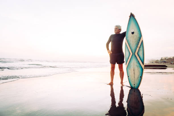 uomo anziano che naviga - senior adult surfing aging process sport foto e immagini stock