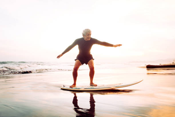 uomo anziano che naviga - senior adult surfing aging process sport foto e immagini stock