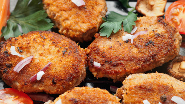 Homemade cutlets with fresh vegetables and herbs close up stock photo
