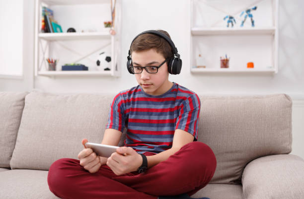 remaja laki-laki bersemangat bermain game mobile di rumah - taruhan bola hari ini potret stok, foto, & gambar bebas royalti