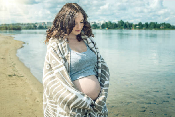 istock Pregnant walks on the river shore. Wrapped in a blanket 850801182
