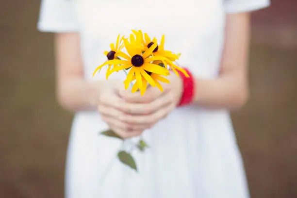 Colourful yellow flowers held by a girl as a gift in a rural setting