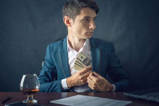 Man Businessman in suit puts money in his pocket. A bribe in the form of dollar bills. Concept of corruption and bribery stock photo