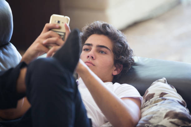 Young Man on Sofa with Cell Phone stock photo