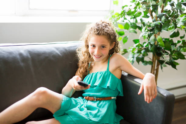 istock Young girl in living room with remote control smiling 850829574