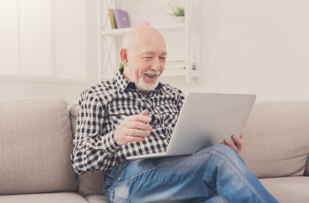 istock Smiling senior man reading news on laptop 850834410