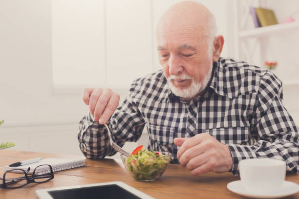 istock Senior man eating fresh salad copy space 850837374