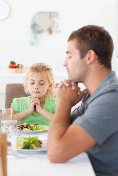 istock Concentrated father and daughter praying before eating their salad 850841666