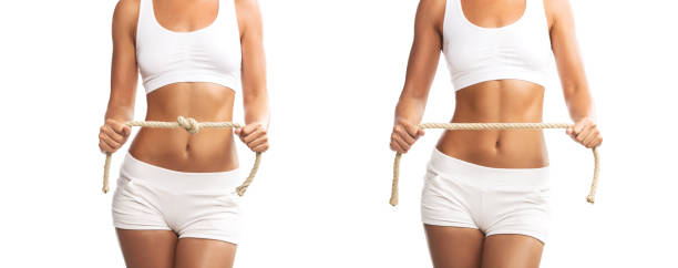 Fit young woman holding a tied and untied rope over her abdomen, isolated on white background Fit young woman holding a tied and untied rope over her abdomen, isolated on white background stomach knot stock pictures, royalty-free photos & images