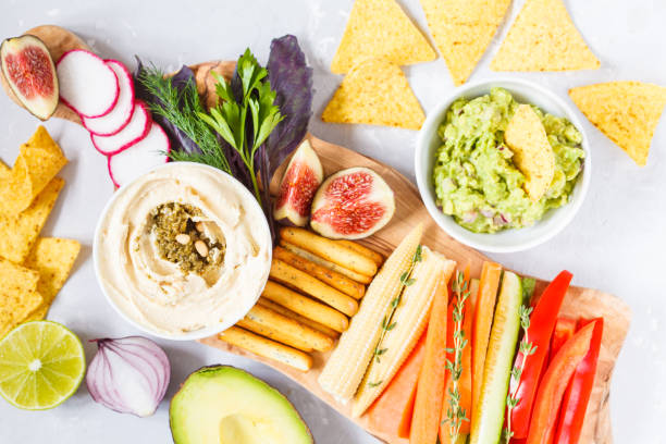 istock Hummus and guacamole with vegetables and snacks on a wooden board 850845414