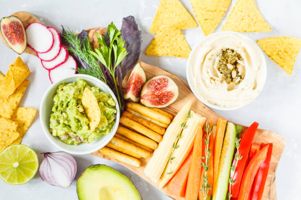 istock Hummus and guacamole with vegetables and snacks on a wooden board 850845554