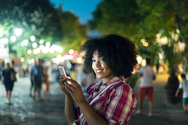 istock Smiling woman using smart phone on street at night 850846256