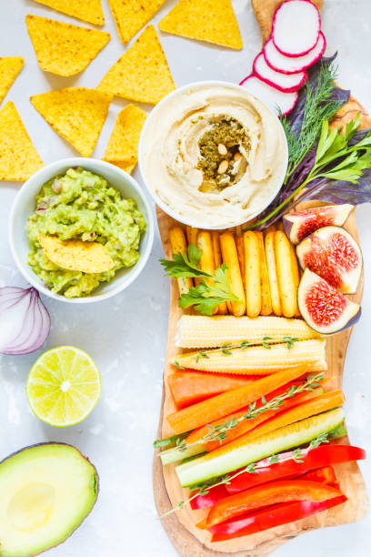 istock Hummus and guacamole with vegetables and snacks on a wooden board 850846300
