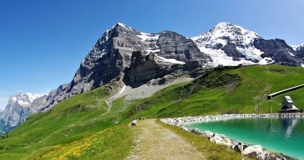 Perspectives on the North Face of the Eiger - a Mountaineering Classic of the Swiss Alps A spectacular series of 25 images of this dramatic 13,000 foot peak, so revered by climbers and mountaineers throughout the world. The challenges posed by the famous, vertical North Face of this dramatic mountain are vividly depicted by these unusual perspectives taken both panoramically and in close-up. The receding glaciers and the perecarious overhangs from the high altitude ice fields illustrate the clear and present avalanche risk with the benign alpine meadows lush and green in high summer providing the picture postcard, chocolate box foreground to these stunning images. The lack of UV haze makes these images appear with outstanding clarity and definition for mountain photography. eiger northface stock pictures, royalty-free photos & images