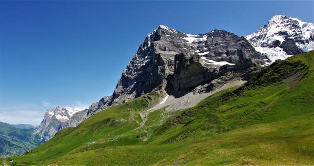 Perspectives on the North Face of the Eiger - a Mountaineering Classic of the Swiss Alps A spectacular series of 25 images of this dramatic 13,000 foot peak, so revered by climbers and mountaineers throughout the world. The challenges posed by the famous, vertical North Face of this dramatic mountain are vividly depicted by these unusual perspectives taken both panoramically and in close-up. The receding glaciers and the perecarious overhangs from the high altitude ice fields illustrate the clear and present avalanche risk with the benign alpine meadows lush and green in high summer providing the picture postcard, chocolate box foreground to these stunning images. The lack of UV haze makes these images appear with outstanding clarity and definition for mountain photography. eiger northface stock pictures, royalty-free photos & images