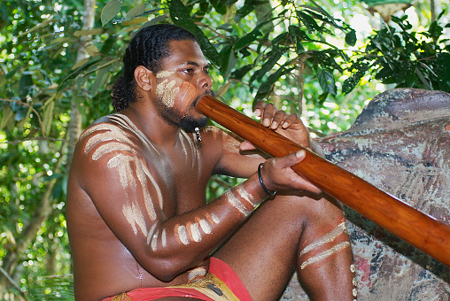 Kuranda, Australia - November 07, 2007: Unidentified aborigine actor performs music with traditional didgeridoo musical instrument in the Tjapukai Culture Park in Kuranda, Queensland, Australia.
