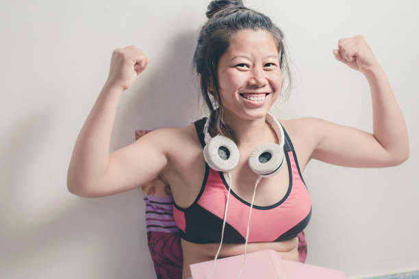 mulher jovem asiática feliz mostrando os músculos dela. - household equipment the human body human limb black hair - fotografias e filmes do acervo